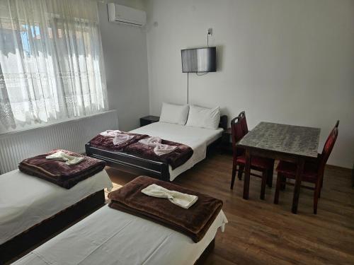 a room with three beds and a table and a table and chairs at Apartments Kuca Aleksic in Niš