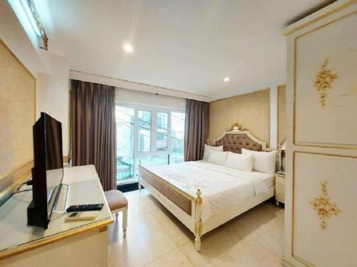 Schlafzimmer mit einem Bett, einem Schreibtisch und einem TV in der Unterkunft Sai Gon Hotel Bui Vien Walking Street in Ho-Chi-Minh-Stadt