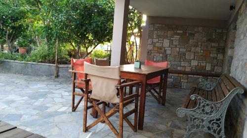 un tavolo e sedie su un patio con panchina di Stone home Lyhna a Líkhna