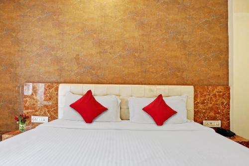 een slaapkamer met een wit bed met rode kussens bij OYO Flagship Bliss Inn in Lukerganj