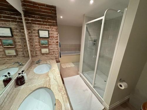 a bathroom with two sinks and a walk in shower at Spacious 4 bed family home near coast in North Creake