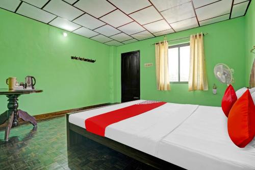 1 dormitorio verde con 1 cama grande con almohadas rojas en Flagship Green Fort Thekkady, en Thekkady