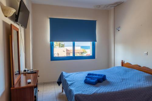 um quarto com uma cama com lençóis azuis e uma janela em Arsinoe Beach Village Block 9 em Pólis