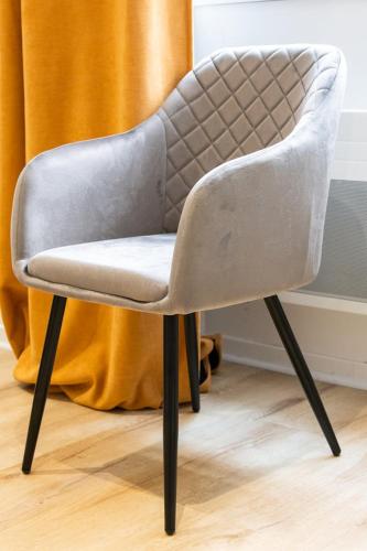 une chaise grise assise dans une pièce à côté d'un rideau dans l'établissement Opéra 9 -Joli studio hypercentre Hôtel de Ville, à Lyon