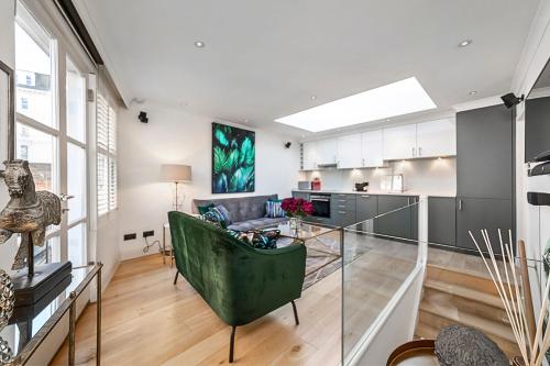 a living room with a green couch and a kitchen at Kensington Oasis Central London 2BR Private House - Near Harrods, Kensington Palace, and other London Attractions in London
