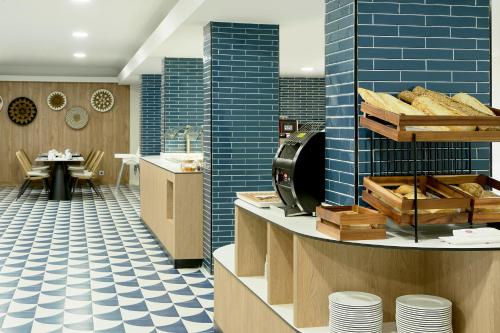 a restaurant with blue tiles and a counter with bread at Exe Portals Nous in Portals Nous