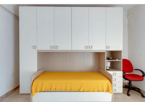 una camera con letto, armadi bianchi e sedia rossa di Casa vacanze Oristano Ghilarza Sardegna a Ghilarza