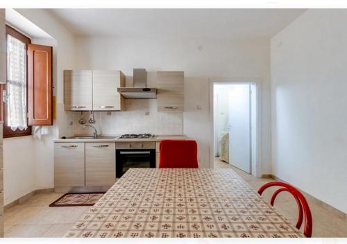 a kitchen with a table and two red chairs at Casa vacanze Oristano Ghilarza Sardegna in Ghilarza