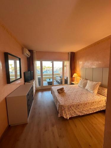 a bedroom with a bed and a television and a balcony at Piso islas C111 in Benalmádena