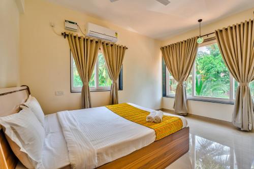 a bedroom with a bed and two windows at Golden Sun Ray's Villas in Baga