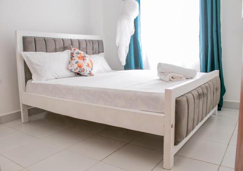 Bett mit weißer Bettwäsche und Kissen in einem Zimmer in der Unterkunft A Cozy 3 Bedroom Apartment With a Pool in Mombasa in Mombasa
