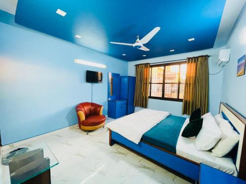 Karachi Inn في كراتشي: غرفة نوم زرقاء مع سرير وكرسي
