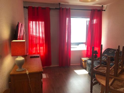 um quarto com cortinas vermelhas, uma secretária e uma janela em plein sud em Saint-Aventin