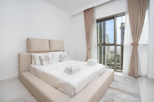 een witte slaapkamer met een groot bed en een groot raam bij 2bdr - Pool - Emaar - Creek Harbour in Dubai