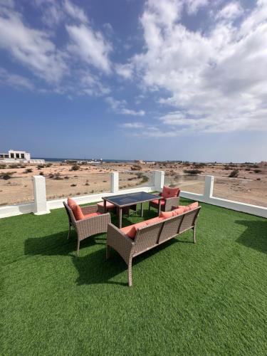 eine Terrasse mit Tisch und Stühlen sowie Strand in der Unterkunft Dibab house in Murrah