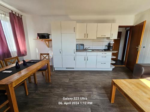 a kitchen with white cabinets and a table and chairs at Ferienwohnung Mond&Wasser 1 in Norden