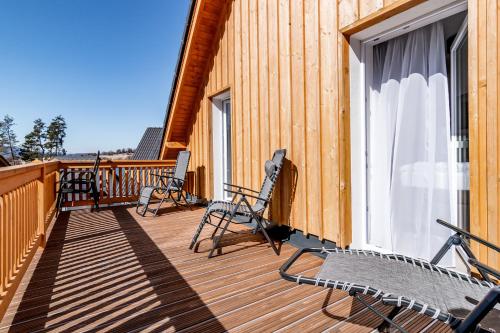 um deque com cadeiras e uma janela numa casa em Lipno Village Houses em Frymburk