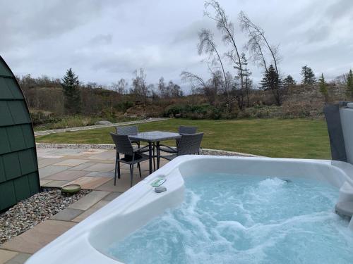a jacuzzi tub in a yard with a table at Tawny Owl Pod with Hot Tub in Oban