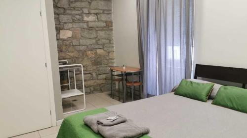 a bedroom with a bed with green sheets and a table at Affittacamere Guerrero Rooms in Trieste