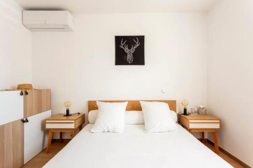 une chambre avec un lit blanc avec deux tables de nuit dans l'établissement Chez Morgane - Charmante maison familiale proche des remparts, à Aigues-Mortes