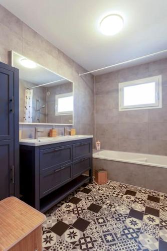 une salle de bain avec une baignoire, un lavabo et un miroir dans l'établissement Chez Morgane - Charmante maison familiale proche des remparts, à Aigues-Mortes