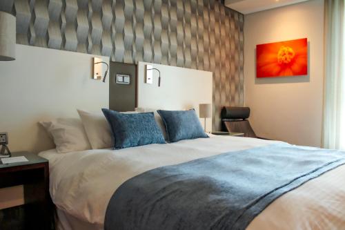 a bedroom with a large bed with blue pillows at Hotel Verde Cape Town Airport in Matroosfontein