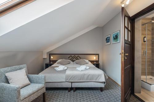 a bedroom with a bed and a chair at Hotel Smile Pieniny in Szczawnica