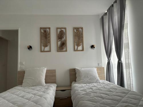 um quarto com duas camas e duas fotografias na parede em Charmant Appt Duplex - 8 Personnes em Saint-Nectaire