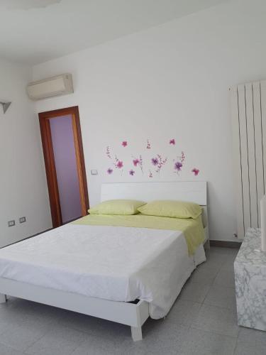 a white bedroom with a bed with flowers on the wall at CASA PRIMO in Villa Rosa