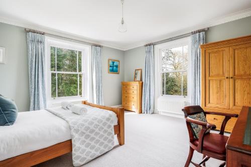 a bedroom with a bed and two windows at Garth Lodge with Tennis Court and Pool in Wimborne Minster