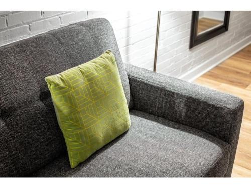 a gray couch with a yellow pillow on it at 2BR 2BA CozySuites in the heart of Indianapolis in Indianapolis
