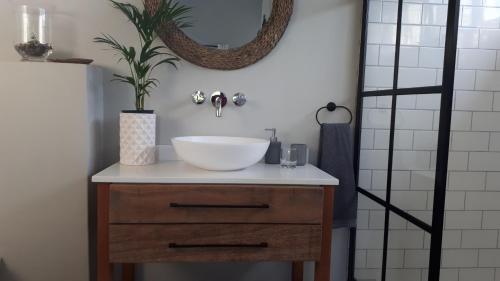 ein Badezimmer mit einem weißen Waschbecken auf einer Holzkommode in der Unterkunft Chapmans Corner Studio in Noordhoek