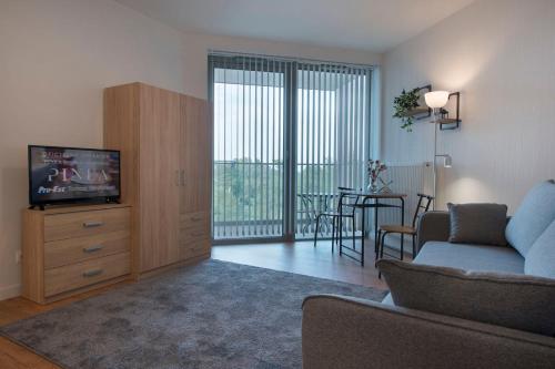 a living room with a couch and a tv and a table at Apartament Deluxe Sea View PINEA 621 in Pobierowo