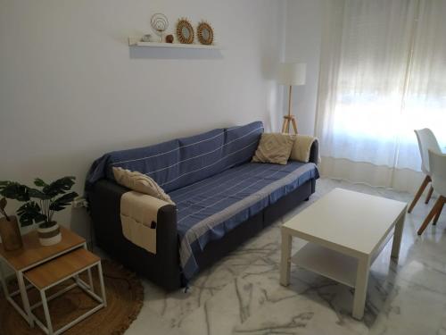 Apartamento en Lux Bormujos في بورموخوس: غرفة معيشة مع أريكة زرقاء وطاولة