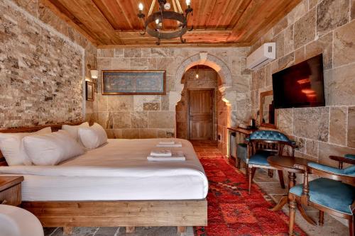 a bedroom with a bed and a desk and a television at Chiaro Boutique Hotel in Uçhisar