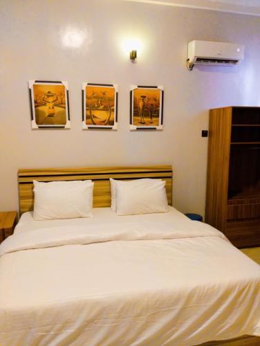 a bedroom with a white bed with four pictures on the wall at MUSAROQ HOTEL in Lagos