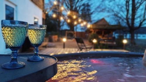 two wine glasses sitting on a table next to a swimming pool at Unique Countryhouse & Sauna in Gauja Valley - Kaķukalns in Straupe