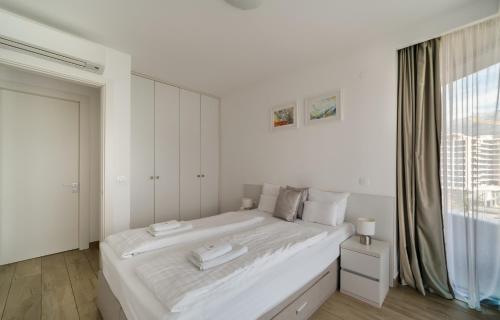 a white bedroom with a large bed and a window at Amare Luxury Apartments in Budva