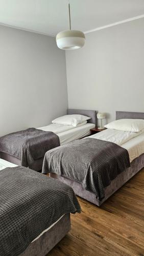 a room with three beds and a lamp at Marel- Apartamenty Rydz Polanica Zdrój in Polanica-Zdrój
