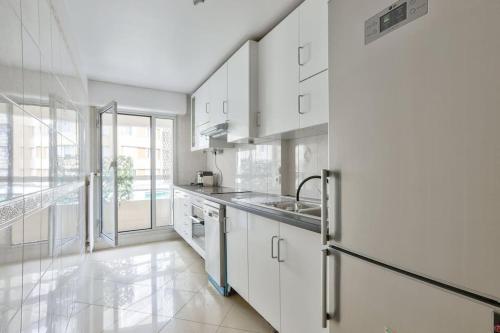 une cuisine avec des placards blancs et une grande fenêtre dans l'établissement Cosy appart avec balcon Pont de Flandres - Crimée, à Paris