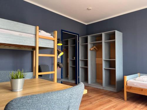 a room with bunk beds and a wooden table at Blue Doors Hostel KTV in Rostock