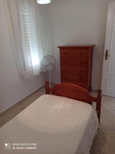 um quarto com uma cama, uma cómoda e uma janela em apartamento em Conil de la Frontera