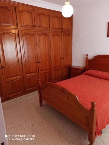 um quarto com uma cama de madeira e armários de madeira em apartamento em Conil de la Frontera