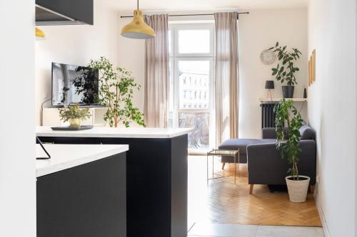 a kitchen with a black and white counter and a living room at Kraków Apartments - Balcony, Workspace, Tram stop - by Rentujemy in Krakow