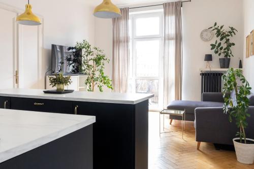 a kitchen with a black and white counter and plants at Kraków Apartments - Balcony, Workspace, Tram stop - by Rentujemy in Krakow