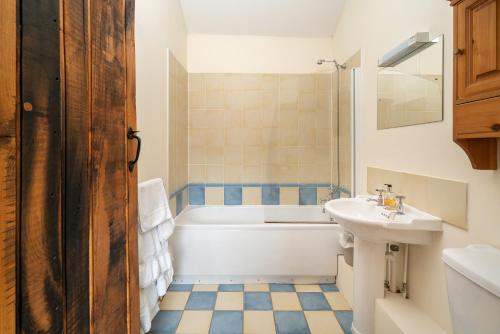 a bathroom with a white tub and a sink at Mill Cottage in Buckinghamshire