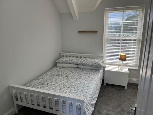 a white bedroom with a bed and a window at Micklefield Lodge in Leeds