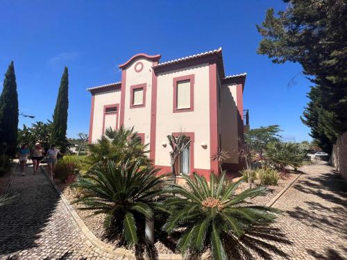 une maison rose avec des palmiers devant elle dans l'établissement Vale da Pinta Golf, à Estômbar