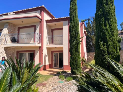 une maison rose avec des arbres devant elle dans l'établissement Vale da Pinta Golf, à Estômbar