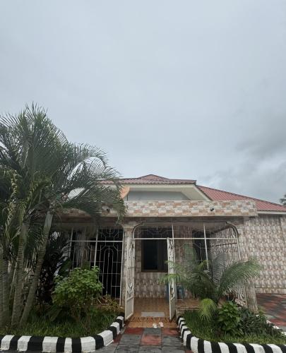 a house with a palm tree in front of it at G & S Executive Lodge in Dar es Salaam